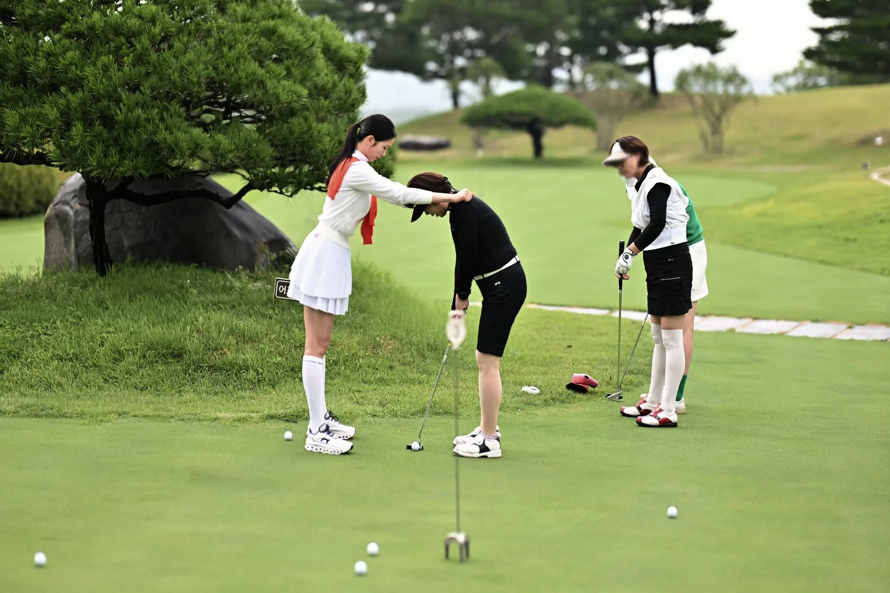 A pro golfer adjusting a guest’s putting posture at a Hanwha golf clinic