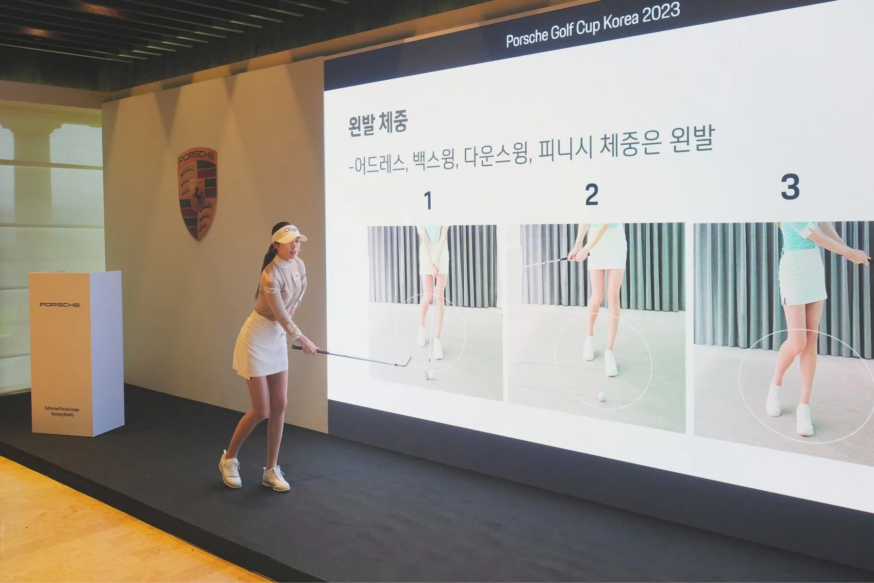 A pro golfer demonstrating swing technique on stage at Porsche Golf Cup Korea