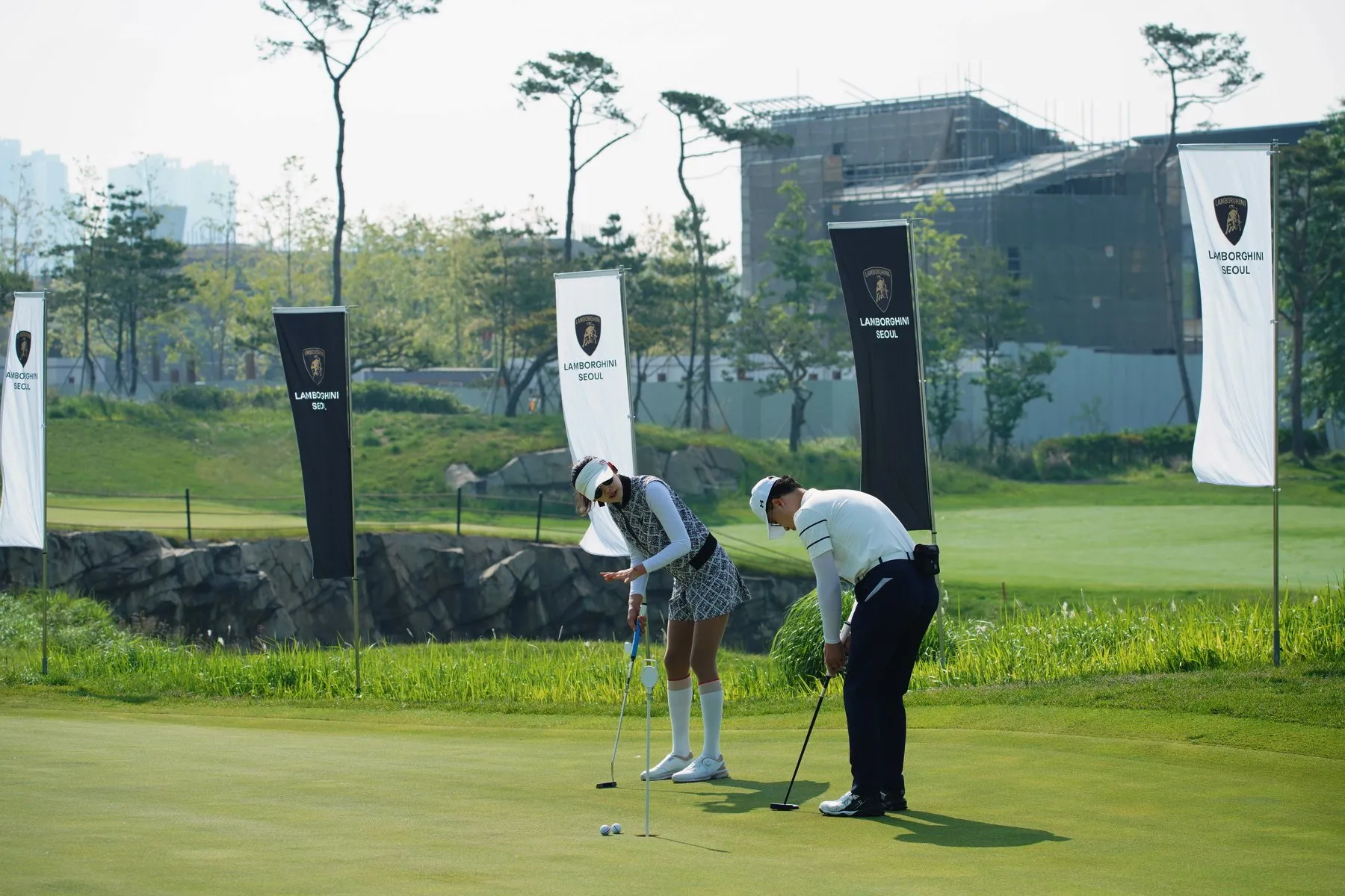 A pro golfer putting alongside a guest at a Lamborghini corporate golf event