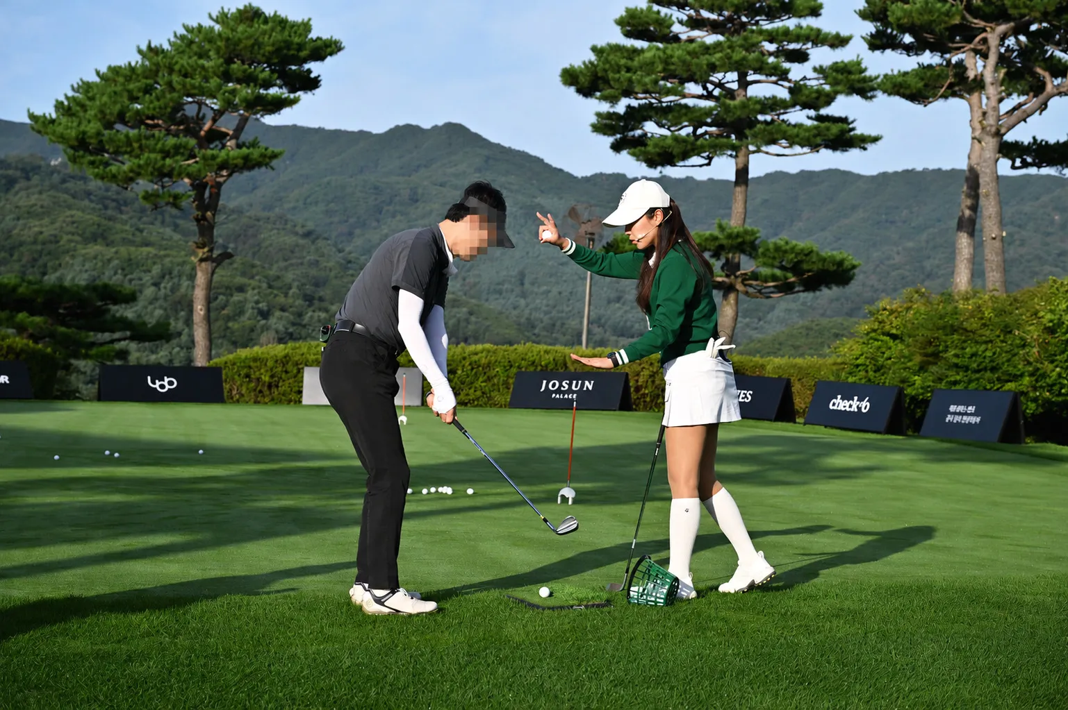 A professional golfer coaching a guest on the course at a corporate golf event