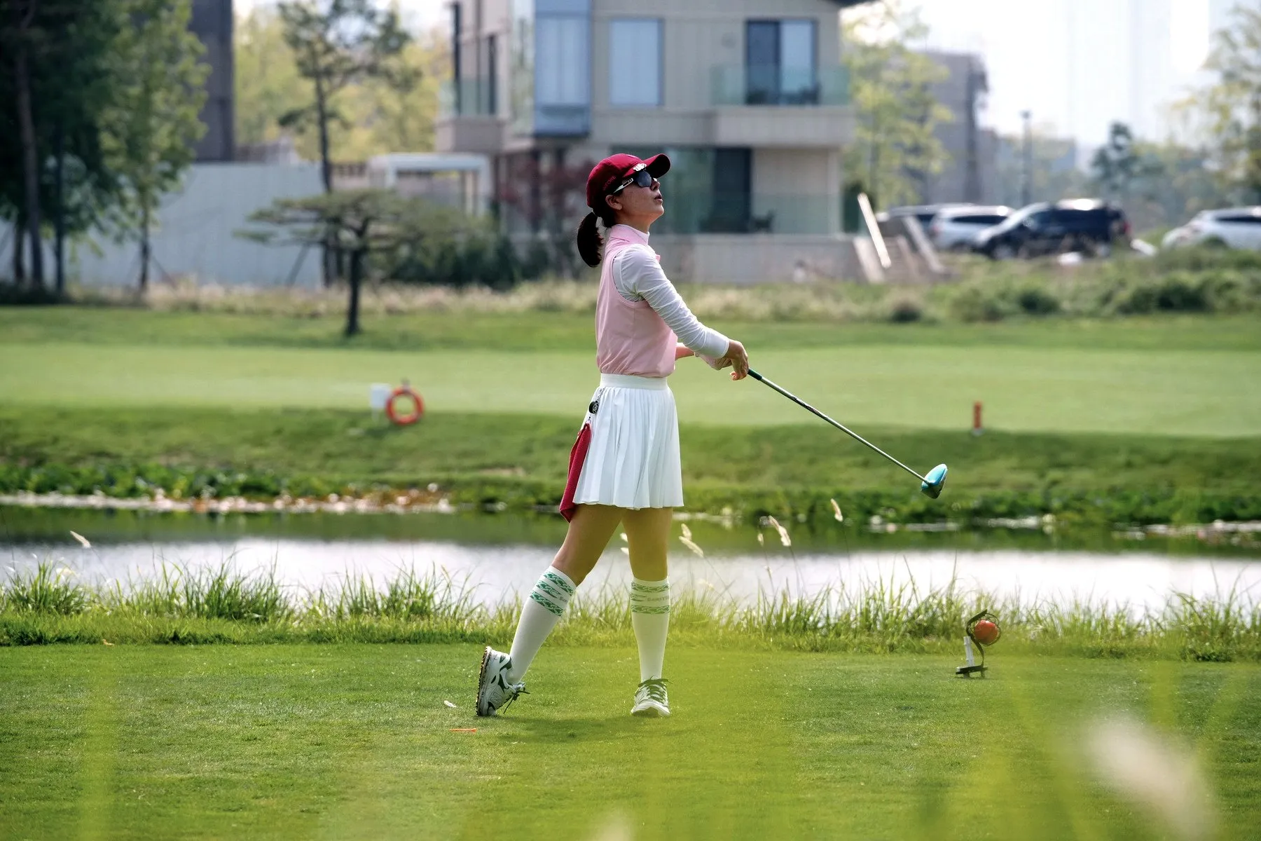 A pro golfer finishing a tee shot beside a lake